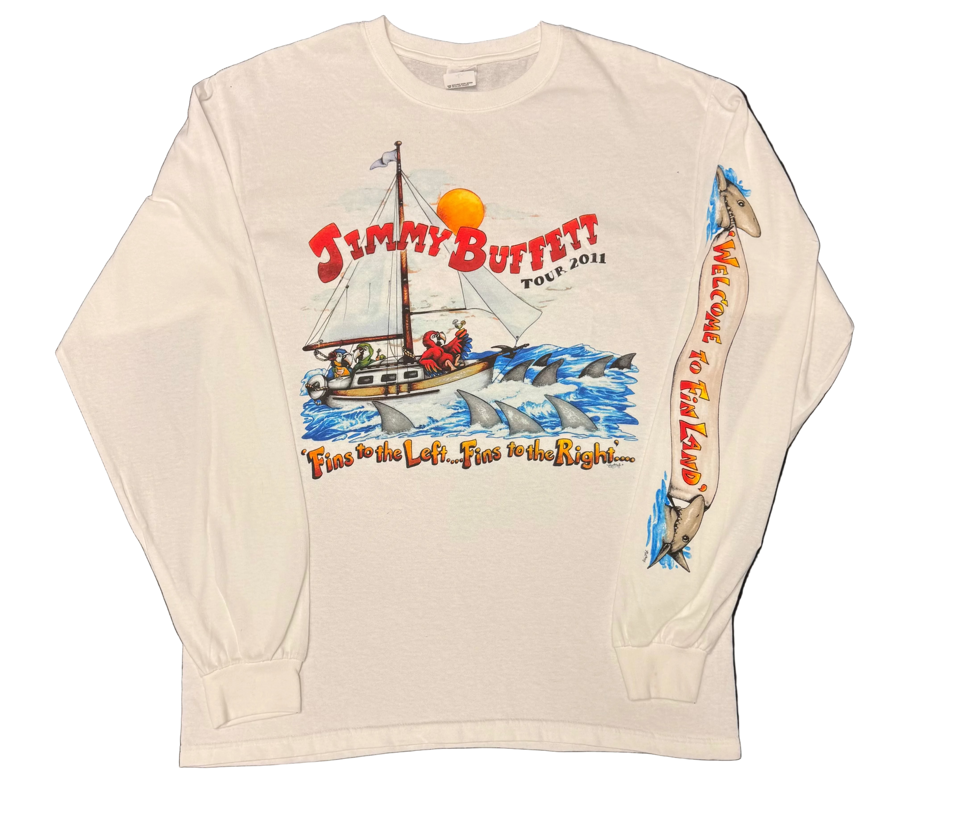 White long sleeve Jimmy Buffett tee featuring a sailboat surrounded by shark fins in blue ocean waves. Red “Jimmy Buffett Tour 2011” lettering appears above, with “Fins to the Left, Fins to the Right…” below. One sleeve features shark graphics and vertical “Welcome to Fin Land” lettering.