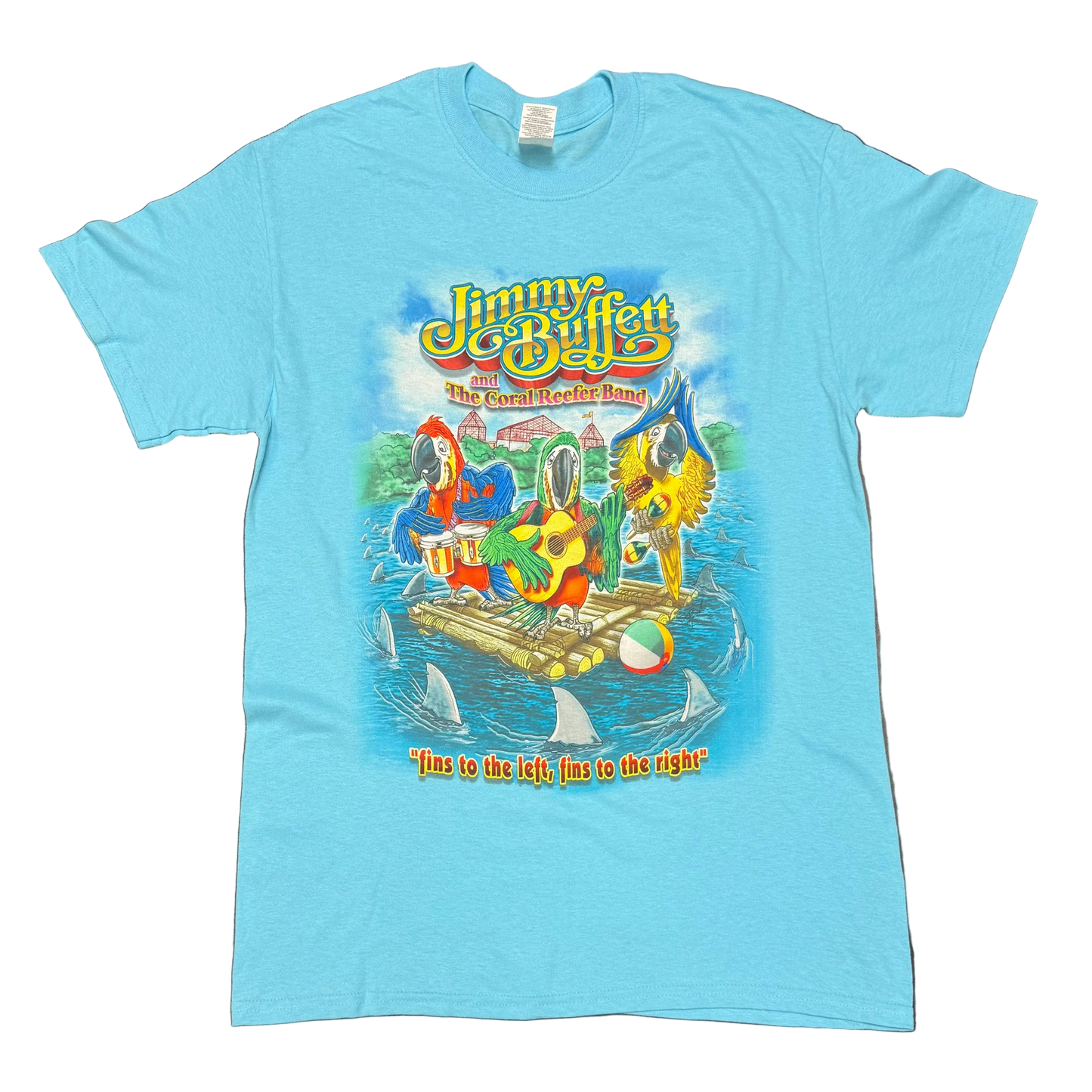 Light blue aqua short sleeve Jimmy Buffett tee featuring Jimmy Buffett and the Coral Reefer Band lettering above three colorful parrots playing drums and guitar on a raft. Shark fins circle the raft in the water, with “fins to the left, fins to the right” printed below the artwork.