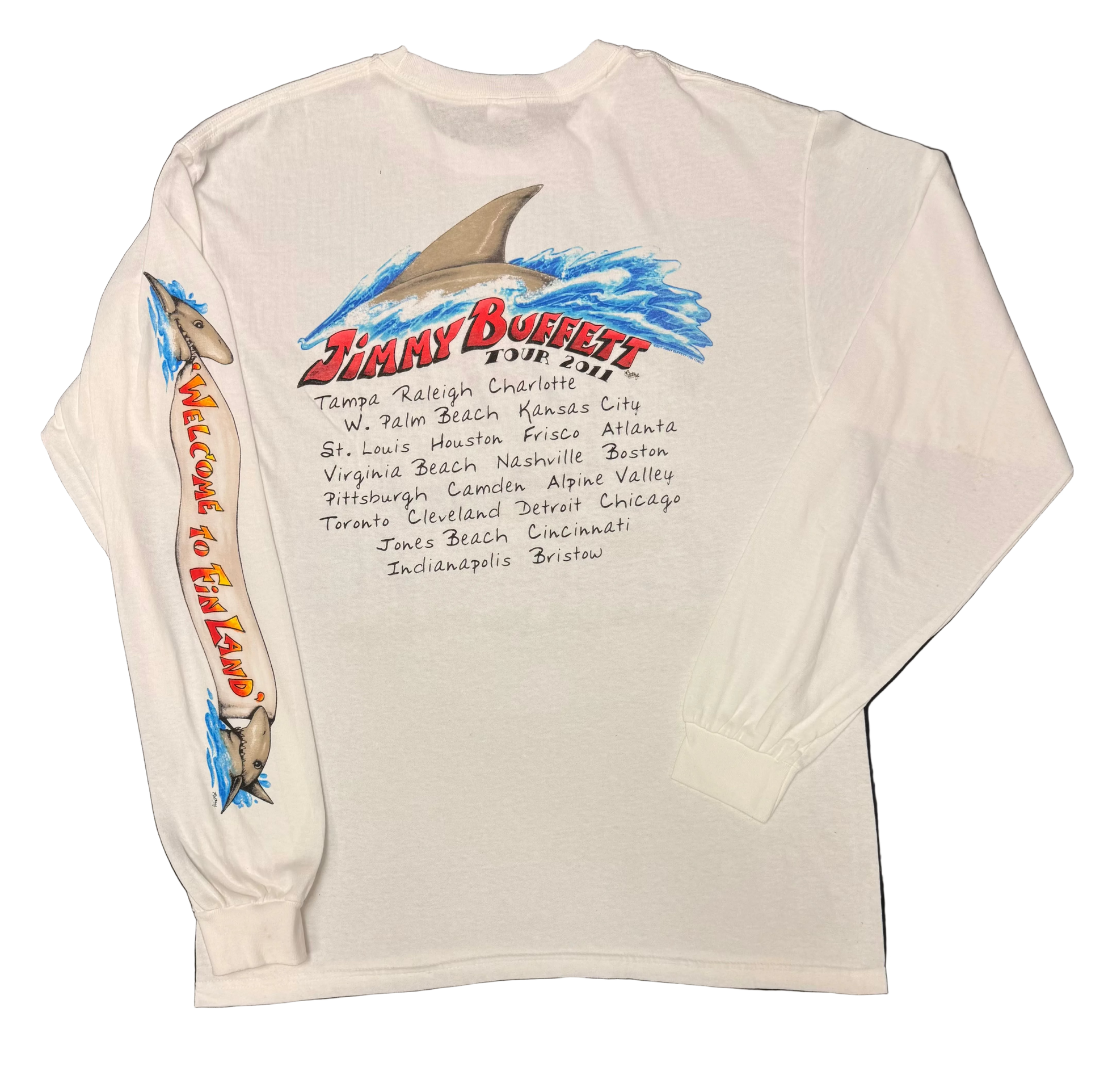 Back of a white long sleeve Jimmy Buffett tee featuring a large shark fin rising through blue waves above red “Jimmy Buffett Tour 2011” lettering and a handwritten style list of tour cities. The sleeve features shark graphics and vertical “Welcome to Fin Land” lettering.