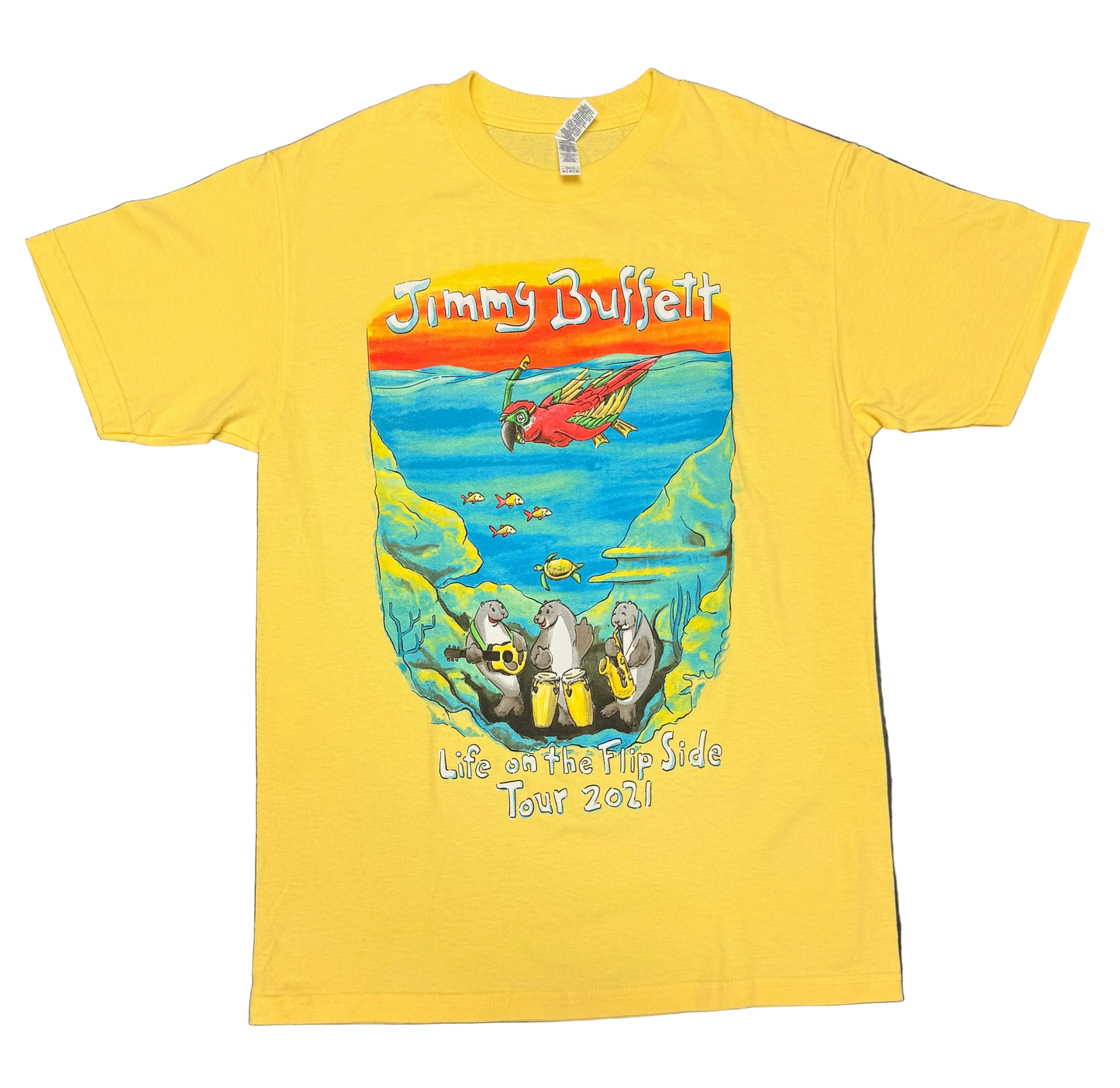 Bright yellow short sleeve Jimmy Buffett tee featuring a colorful underwater scene with a red parrot swimming above tropical fish and a sea turtle. Three manatees play guitar, congas, and saxophone along the ocean floor, with “Jimmy Buffett” above and “Life on the Flip Side Tour 2021” below.