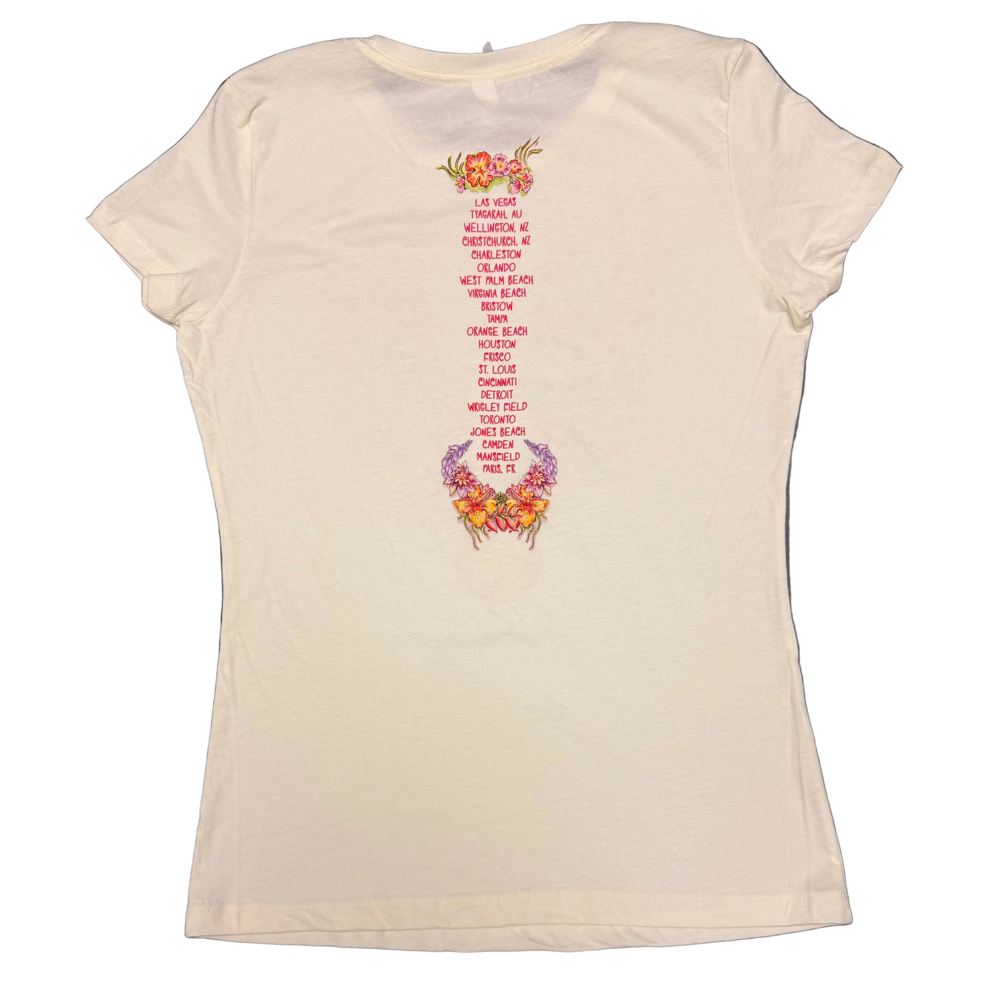 Back of a cream women’s short sleeve Jimmy Buffett tee featuring a vertical list of 2017 tour cities printed in red. Tropical floral accents in pink, purple, and orange appear above and below the city list.