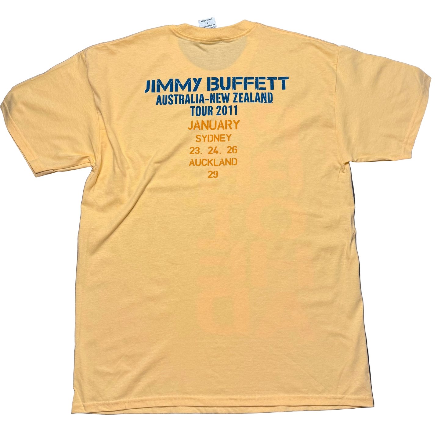 Back of a light yellow short sleeve Jimmy Buffett tee featuring blue “Jimmy Buffett Australia New Zealand Tour 2011” lettering above orange tour date text. The design lists January performances in Sydney on the 23rd, 24th, and 26th, and Auckland on the 29th.